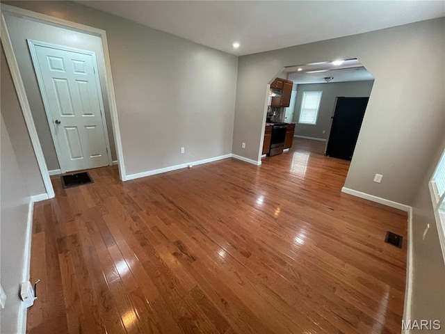 6155 Emerald Ave, Saint Louis, MO 63135 - unfurnished living room featuring light wood-style floors, arched walkways, and recessed lighting