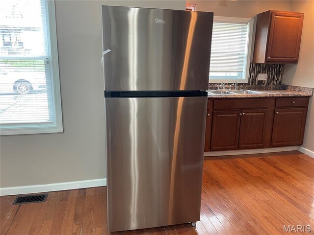 6155 Emerald Ave, Saint Louis, MO 63135 - kitchen with freestanding refrigerator, light wood finished floors, dark countertops, and backsplash