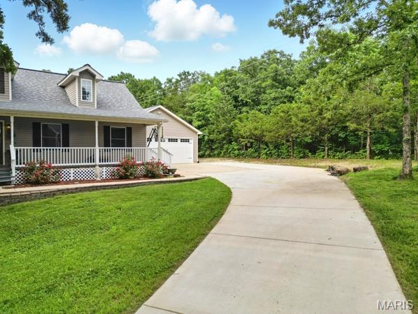 9 Sun Trail, Rise Trail, MO 63050 - view of front facade with covered porch, a front lawn, driveway, and a shingled roof