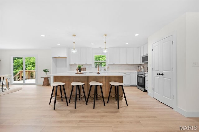 178 Spring Branch Rd, Troy, MO 63379 - kitchen featuring appliances with stainless steel finishes, a kitchen island, light wood finished floors, white cabinets, and light countertops
