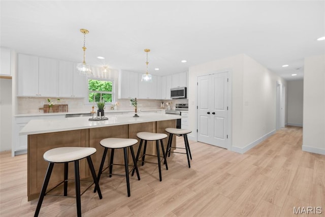 178 Spring Branch Rd, Troy, MO 63379 - kitchen featuring appliances with stainless steel finishes, light wood-type flooring, white cabinets, a kitchen island, and recessed lighting