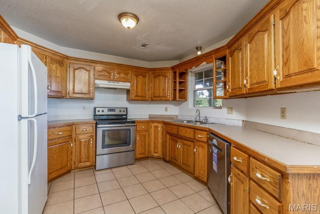 19395 Ripley Dr, Lebanon, MO 65536 - kitchen with appliances with stainless steel finishes, a sink, under cabinet range hood, brown cabinets, and light tile patterned flooring