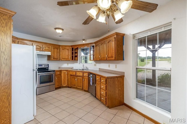 19395 Ripley Dr, Lebanon, MO 65536 - kitchen with stainless steel appliances, a sink, under cabinet range hood, light tile patterned floors, and brown cabinetry