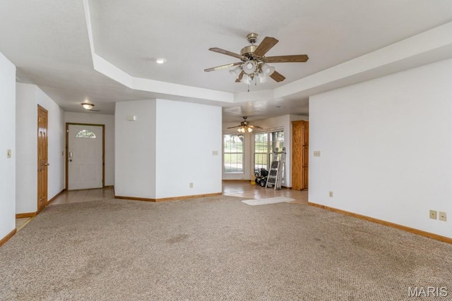 19395 Ripley Dr, Lebanon, MO 65536 - unfurnished living room with baseboards, a raised ceiling, light carpet, and ceiling fan