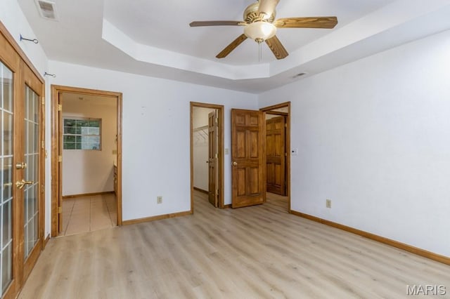 19395 Ripley Dr, Lebanon, MO 65536 - unfurnished bedroom featuring light wood-type flooring, a tray ceiling, french doors, and baseboards