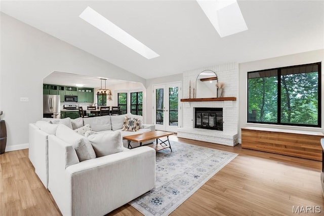 62 Majestic Ct, Fenton, MO 63026 - living room featuring a skylight, light wood-style flooring, high vaulted ceiling, and a brick fireplace