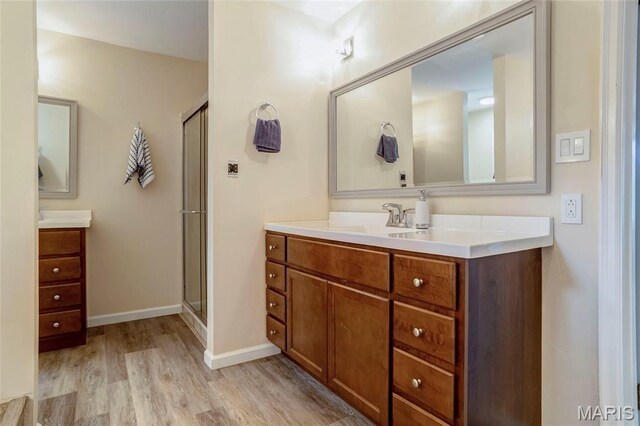 17560 Old Jamestown Rd, Florissant, MO 63034 - full bathroom with wood finished floors, two vanities, a shower stall, and baseboards