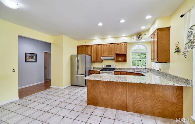 4 Hahn Estates Rd, Winfield, MO 63389 - kitchen with stainless steel appliances, a peninsula, under cabinet range hood, light tile patterned flooring, and light stone countertops