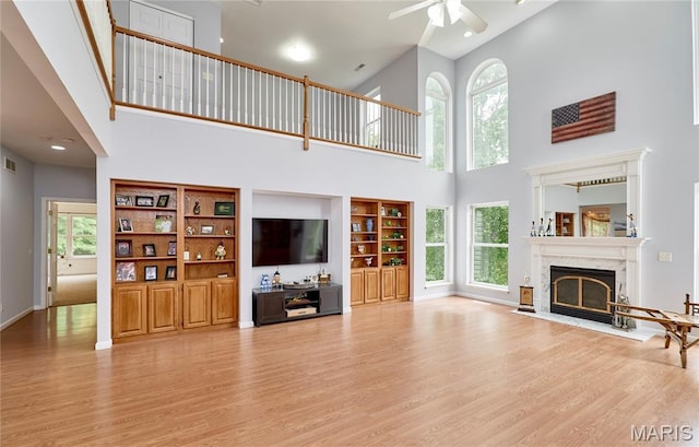 4 Hahn Estates Rd, Winfield, MO 63389 - unfurnished living room with a towering ceiling, wood finished floors, a ceiling fan, plenty of natural light, and a high end fireplace
