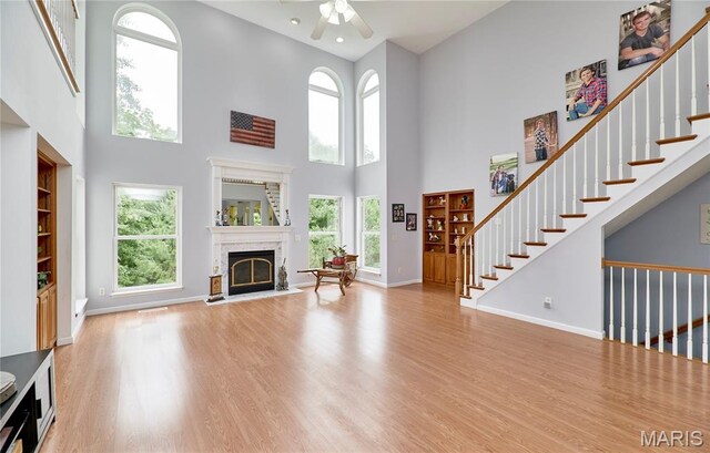 4 Hahn Estates Rd, Winfield, MO 63389 - living room featuring a fireplace with flush hearth, a high ceiling, wood finished floors, ceiling fan, and stairway
