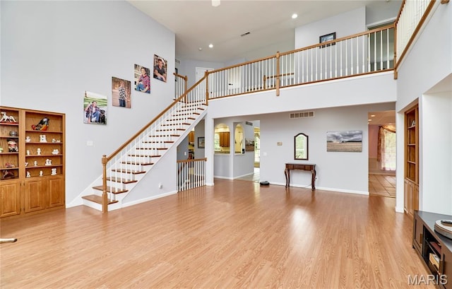 4 Hahn Estates Rd, Winfield, MO 63389 - unfurnished living room featuring a high ceiling, stairs, light wood finished floors, and recessed lighting