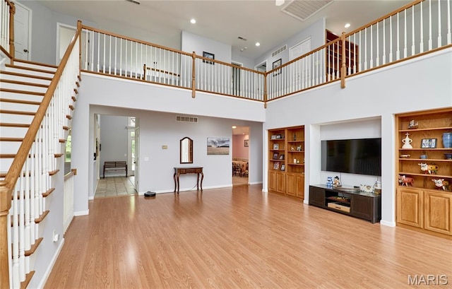 4 Hahn Estates Rd, Winfield, MO 63389 - unfurnished living room featuring a towering ceiling, stairs, light wood finished floors, and recessed lighting