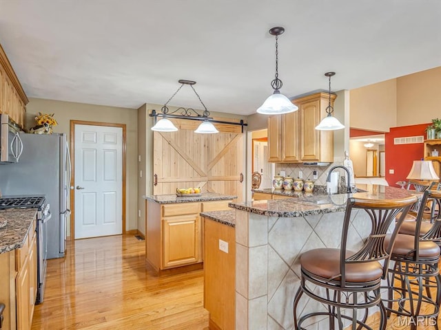 4184 Red Field Dr, Swansea, IL 62226 - kitchen featuring stainless steel appliances, a barn door, a peninsula, light wood-style floors, and decorative backsplash