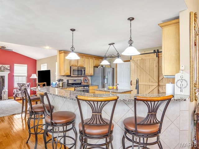 4184 Red Field Dr, Swansea, IL 62226 - kitchen with appliances with stainless steel finishes, a peninsula, light wood-type flooring, light brown cabinets, and vaulted ceiling