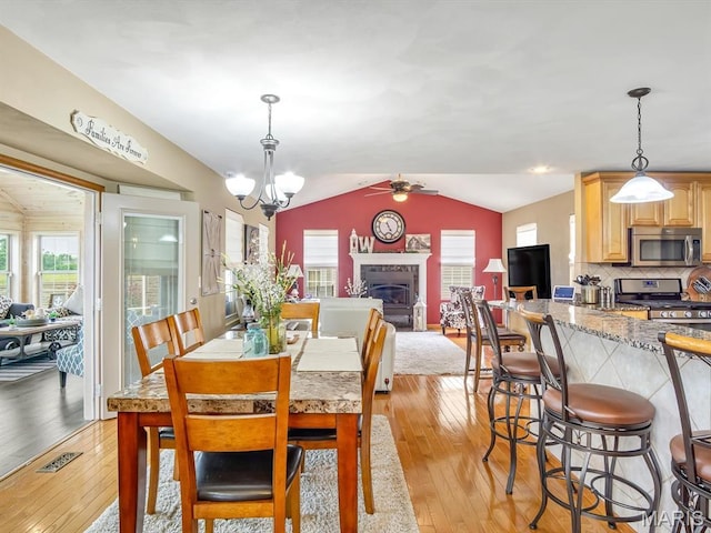 4184 Red Field Dr, Swansea, IL 62226 - dining area featuring light wood-style floors, lofted ceiling, a glass covered fireplace, a ceiling fan, and a chandelier