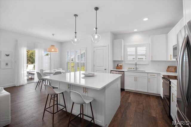 111 Creek Haven Ct, Lake St Louis, MO 63367 - kitchen featuring stainless steel appliances, a sink, a kitchen bar, a center island, and dark wood-style flooring