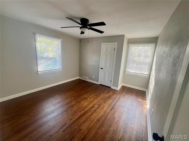 2328 Rockdale Ave, Saint Louis, MO 63121 - unfurnished bedroom featuring dark wood finished floors, multiple windows, baseboards, and a ceiling fan