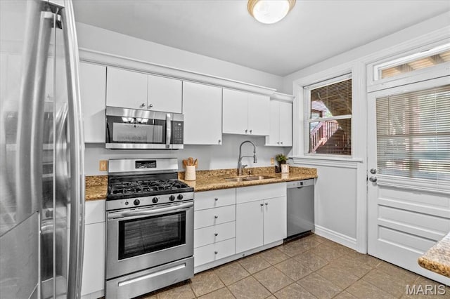 6318 Southwood Ave Unit 1W, Saint Louis, MO 63105 - kitchen featuring appliances with stainless steel finishes, a sink, baseboards, white cabinets, and light stone countertops
