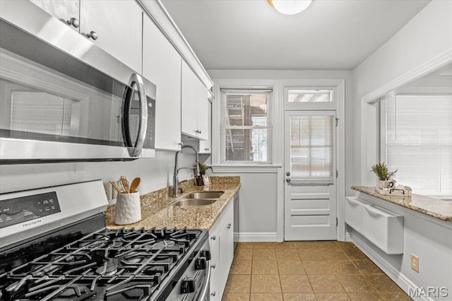 6318 Southwood Ave Unit 1W, Saint Louis, MO 63105 - kitchen with stainless steel appliances, light tile patterned flooring, a sink, white cabinetry, and baseboards
