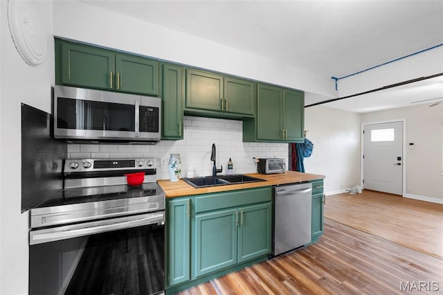 2604 Tamm Ave, Saint Louis, MO 63139 - kitchen featuring stainless steel appliances, green cabinets, butcher block countertops, backsplash, and light wood finished floors