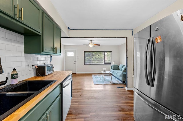 2604 Tamm Ave, Saint Louis, MO 63139 - kitchen featuring green cabinetry, appliances with stainless steel finishes, butcher block countertops, decorative backsplash, and dark wood-style floors
