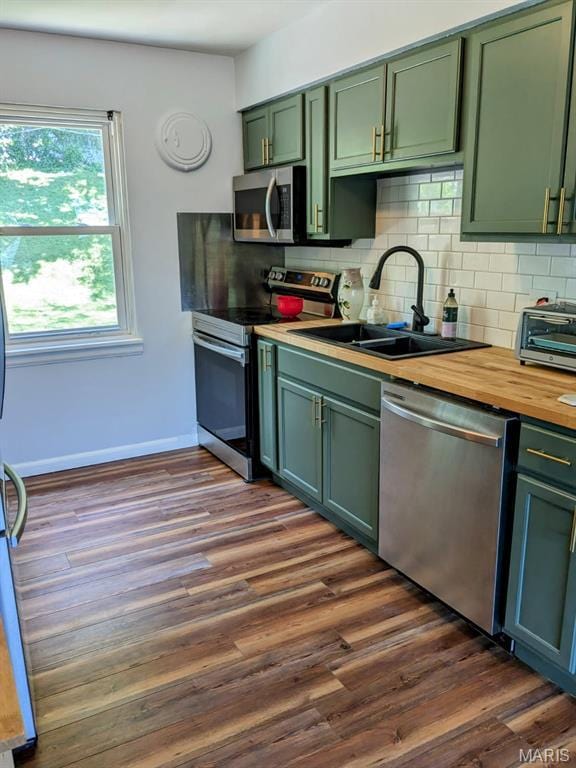 2604 Tamm Ave, Saint Louis, MO 63139 - kitchen with appliances with stainless steel finishes, green cabinetry, tasteful backsplash, and dark wood-type flooring