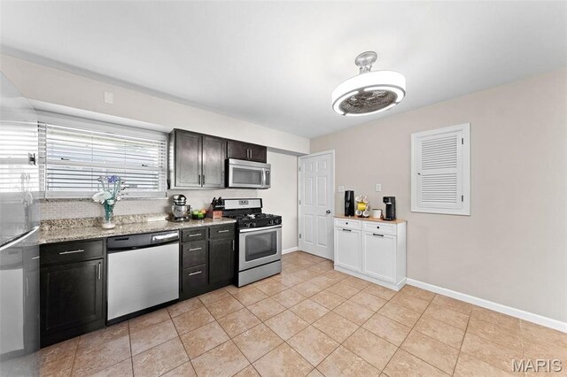 4620 Kramer Dr, Saint Louis, MO 63123 - kitchen featuring appliances with stainless steel finishes, light tile patterned floors, light stone countertops, and dark cabinets