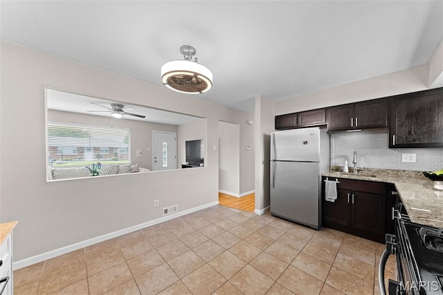4620 Kramer Dr, Saint Louis, MO 63123 - kitchen with freestanding refrigerator, gas stove, decorative backsplash, light stone countertops, and dark brown cabinets