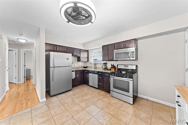 4620 Kramer Dr, Saint Louis, MO 63123 - kitchen featuring appliances with stainless steel finishes, dark brown cabinets, light stone counters, and light tile patterned floors