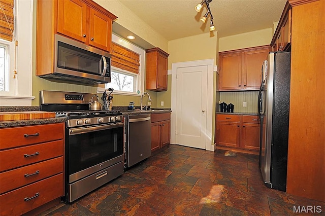 1425 Perryville Cpe, Girardeau, MO 63701 - kitchen with appliances with stainless steel finishes, brown cabinets, a sink, and dark stone finish floors