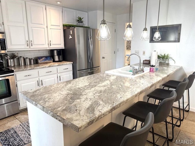 63 Rock Dove Ln, Camdenton, MO 65020 - kitchen with appliances with stainless steel finishes, a sink, white cabinetry, backsplash, and a breakfast bar