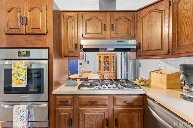 611 Park St, Farmington, MO 63640 - kitchen featuring appliances with stainless steel finishes, under cabinet range hood, brown cabinetry, and light countertops