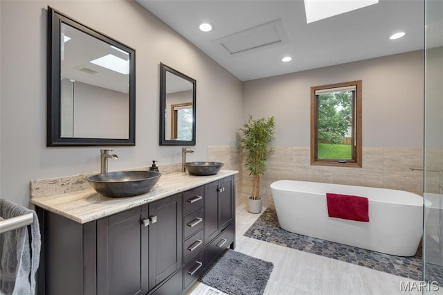 1509 Redbriar Dr, High Ridge, MO 63049 - bathroom with a freestanding tub, double vanity, tile walls, wainscoting, and recessed lighting