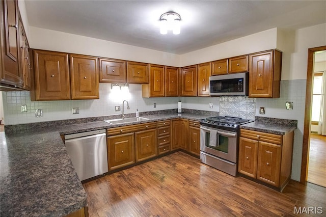 10000 Wondell Woods Dr, Belleville, IL 62223 - kitchen with stainless steel appliances, brown cabinetry, dark countertops, decorative backsplash, and dark wood finished floors