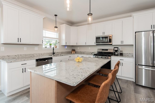 509 Spruce Hollow Ct, Wentzville, MO 63385 - kitchen featuring stainless steel appliances, wood finished floors, a breakfast bar area, a kitchen island, and ornamental molding