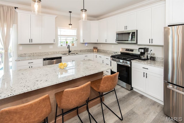 509 Spruce Hollow Ct, Wentzville, MO 63385 - kitchen featuring stainless steel appliances, a breakfast bar, ornamental molding, white cabinetry, and light wood-style floors