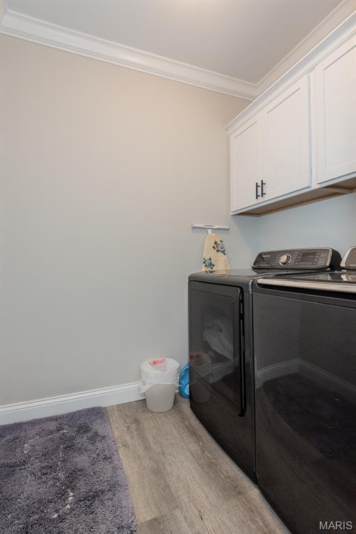 509 Spruce Hollow Ct, Wentzville, MO 63385 - washroom featuring washer and dryer, ornamental molding, cabinet space, and light wood finished floors