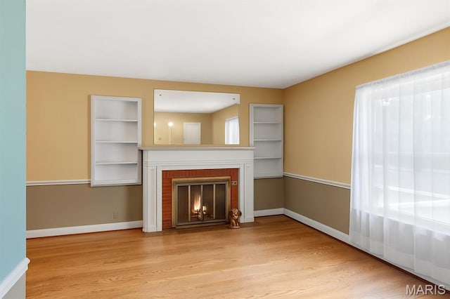 914 Trelane Ave, Crestwood, MO 63126 - unfurnished living room with light wood-type flooring, a brick fireplace, and built in shelves