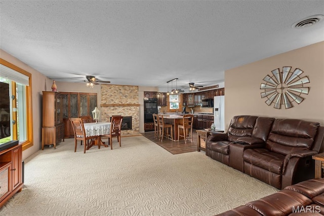 900 Montana St, Gillespie, IL 62033 - living room featuring ceiling fan, a textured ceiling, a fireplace, and light carpet
