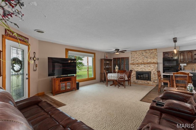 900 Montana St, Gillespie, IL 62033 - living room featuring a textured ceiling, ceiling fan, a fireplace, and light colored carpet