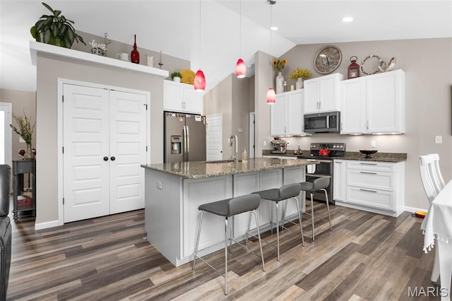 815 Mule Creek Dr, Wentzville, MO 63385 - kitchen with stainless steel appliances, dark wood-style flooring, white cabinetry, an island with sink, and a kitchen bar