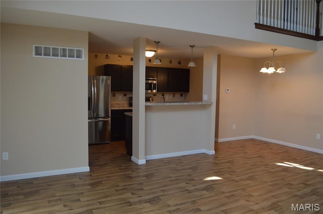 1313 Commons Cir, Cottleville, MO 63304 - kitchen with stainless steel appliances, dark wood finished floors, light countertops, a chandelier, and decorative light fixtures