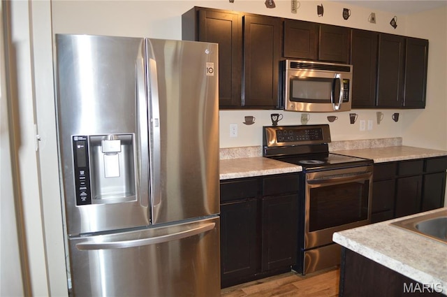 1313 Commons Cir, Cottleville, MO 63304 - kitchen featuring appliances with stainless steel finishes, light countertops, light wood-style flooring, and dark brown cabinets