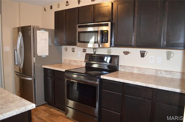 1313 Commons Cir, Cottleville, MO 63304 - kitchen with stainless steel appliances, light countertops, light wood-type flooring, and dark brown cabinets