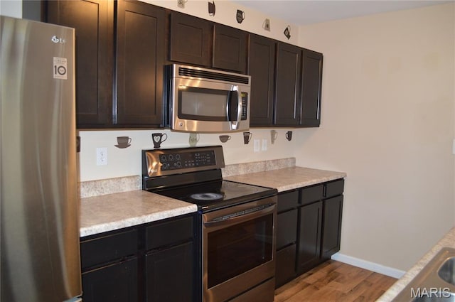 1313 Commons Cir, Cottleville, MO 63304 - kitchen with appliances with stainless steel finishes, light wood-type flooring, light countertops, and dark brown cabinetry