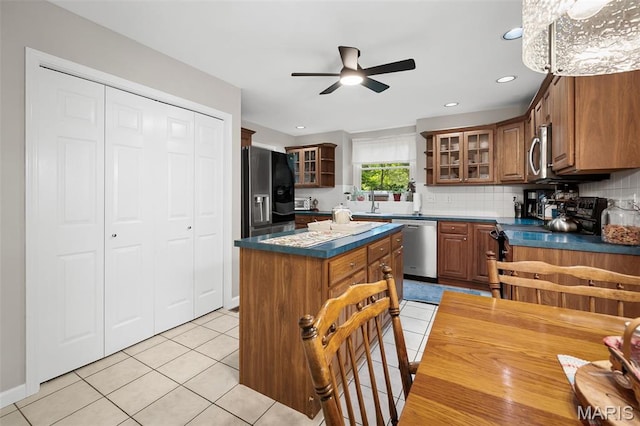 20220 Inverness Dr, Marthasville, MO 63357 - kitchen featuring appliances with stainless steel finishes, a ceiling fan, dark countertops, a kitchen island, and tasteful backsplash