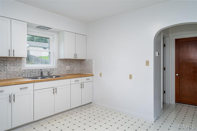 1407 E 5th St, Washington, MO 63090 - kitchen with wood counters, decorative backsplash, arched walkways, and white cabinetry