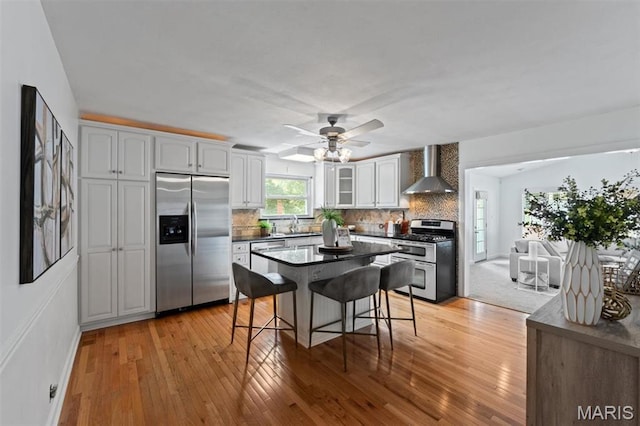 12330 Cape Cod Dr, Creve Coeur Township, MO 63146 - kitchen with stainless steel appliances, wall chimney exhaust hood, dark countertops, a breakfast bar, and glass insert cabinets