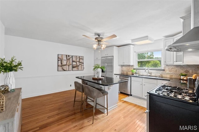 12330 Cape Cod Dr, Creve Coeur Township, MO 63146 - kitchen with stainless steel appliances, wall chimney exhaust hood, a breakfast bar, and light wood-style floors