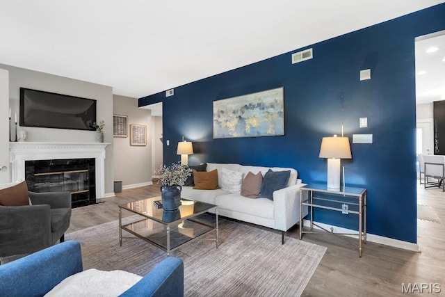 5858 Nina Pl # 1W, Saint Louis, MO 63112 - living area featuring an accent wall, wood finished floors, and a high end fireplace